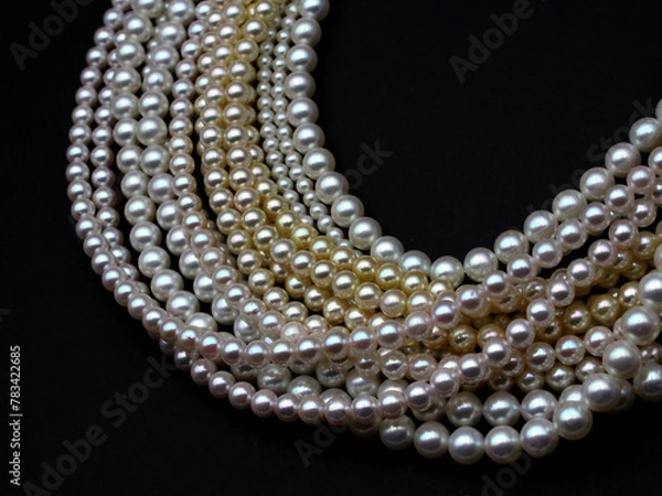 Fototapeta Expensive and luxurious Japanese saltwater Akoya pearls on strands of white, pink and golden organic gems ready to be made into necklaces and sold in jewelry store.