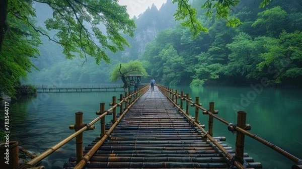 Fototapeta A tranquil scene of a bamboo bridge stretching across a serene river, with a diverse couple strolling hand in hand, leaving room for inspirational text.