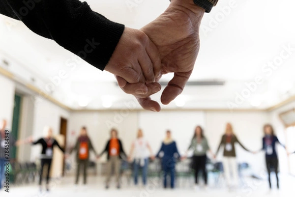 Fototapeta hands shaking in a round circle with blurry people in the background