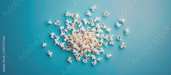 Fototapeta Popcorn spilled on a blue background.