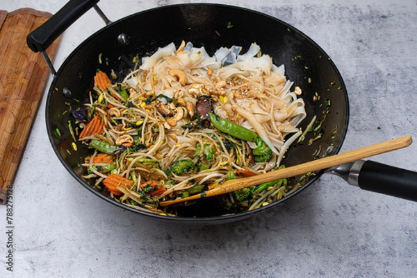 Fototapeta Cast iron wok with noodles and vegan stir fry,