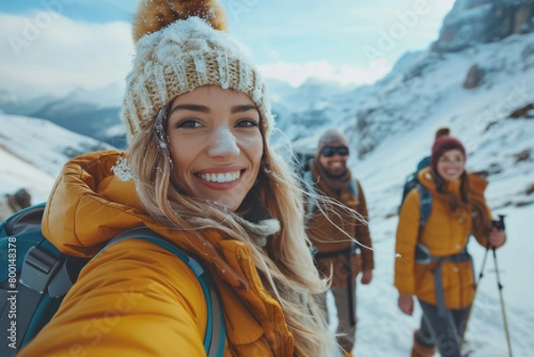 Fototapeta Happy woman in warm clothes taking a selfie with your friends while looking at screen in mountain background