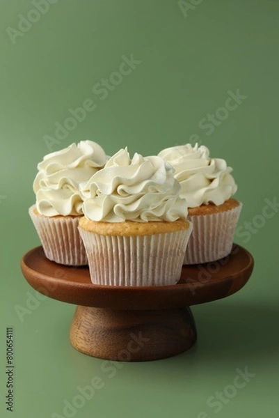 Obraz Tasty vanilla cupcakes with cream on green background