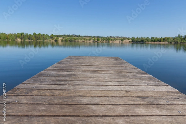 Obraz A dock on the lake on the sunny day with nice clean reflection of the forrest behind