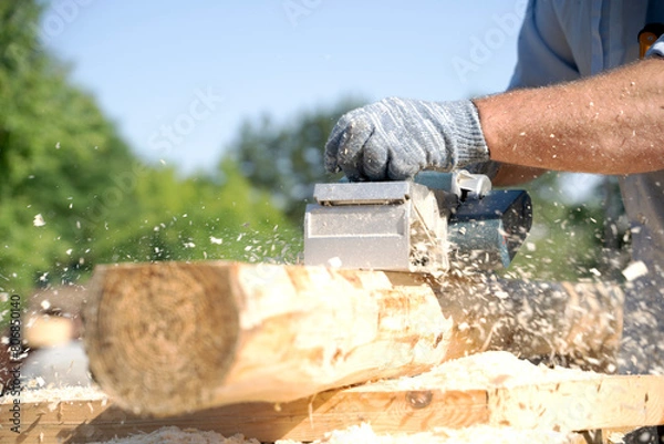 Fototapeta a carpenter works with an electric pipe on a sunny day