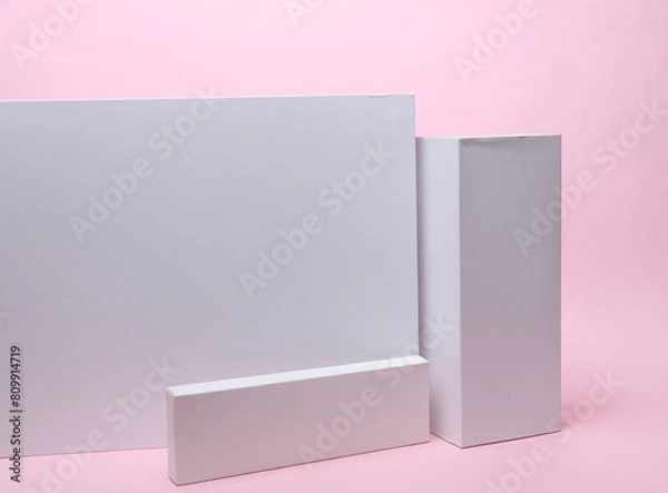 Fototapeta Different shapes of white cardboard boxes for presentation products on pink background. Mockup for design.