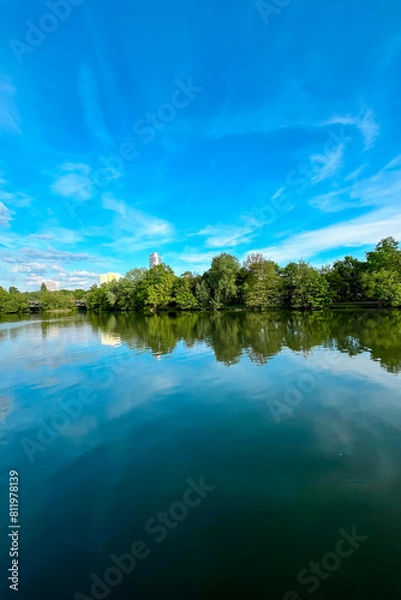 Fototapeta Lake Wohrder, a beach view of the lake from the shore in Nuremberg. Fantastic view of the reflection of trees and blue sky in the water