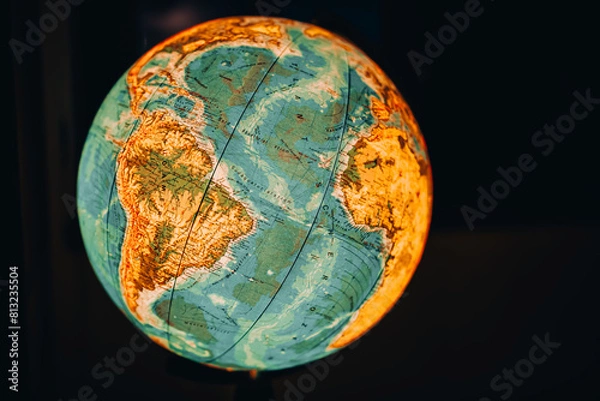 Fototapeta Geography study.Glowing globe on a dark background. Cities and countries on the globe. Travel around the globe.