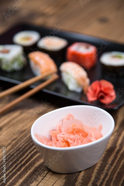 Fototapeta Sushi pieces collection with bamboo chopsticks, isolated on wooden table