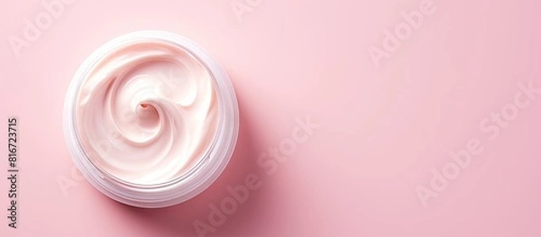 Fototapeta Top view of a moisturizer with a half opened lid placed on a light pink background in a flat lay style with copy space image