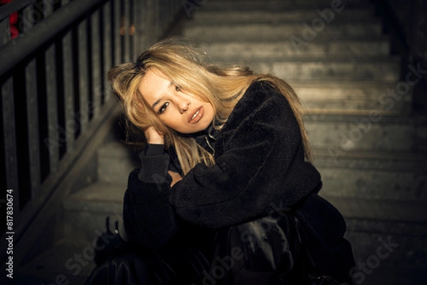 Fototapeta Caucasian attractive woman in black grunge attire posing on the staircase