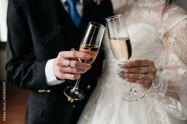 Fototapeta two glasses of champagne in the bride's hands