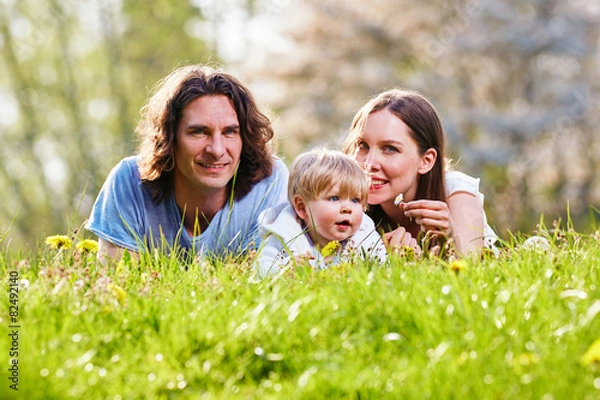 Fototapeta Junge Familie gemeinsam im Gras auf der Wiese