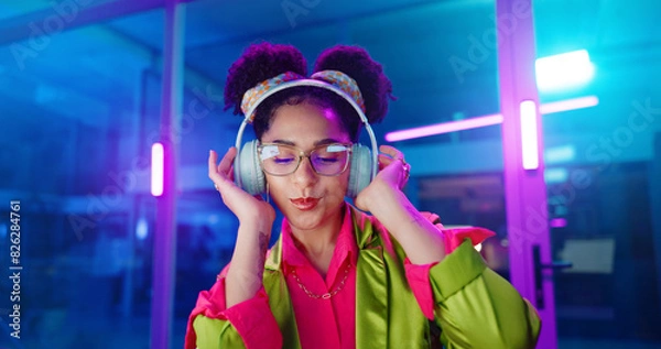 Fototapeta Woman, night and headphones for music, glasses and dancing for motivation in office. Happy female person, hip hop playlist and movement in neon light, connection and streaming radio while working