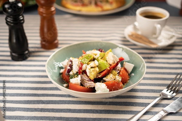 Fototapeta Fresh vegetable salad with avocado and feta cheese on the table served in a cafe for breakfast with cutlery. Healthy breakfast and diet