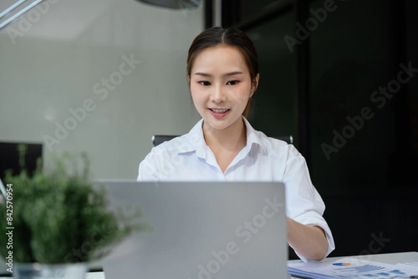 Fototapeta Successful business woman using smartphone and digital tablet, laptop computer in modern business office.