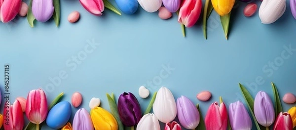 Fototapeta A flat lay banner featuring a vibrant Easter composition composed of tulip petals feathers and egg shells with plenty of copy space for captions or text