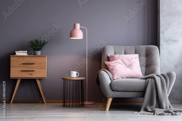 Fototapeta A gray armchair with pink pillows near a gray wall, with a bed, a wall in the interior of a spacious bedroom with a blanket on the bed next to a pink lamp.