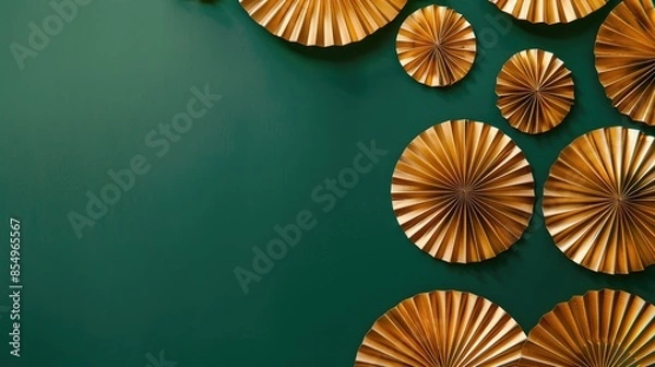 Fototapeta Festive gold paper fans on green backdrop with space for text