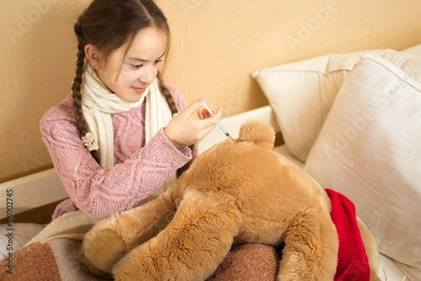 Obraz girl playing with brown teddy bear and making injection