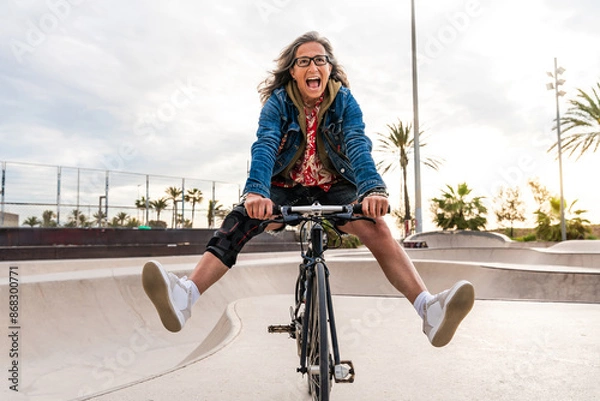 Fototapeta Beautiful confident senior woman with grey hair skateboarding outdoors