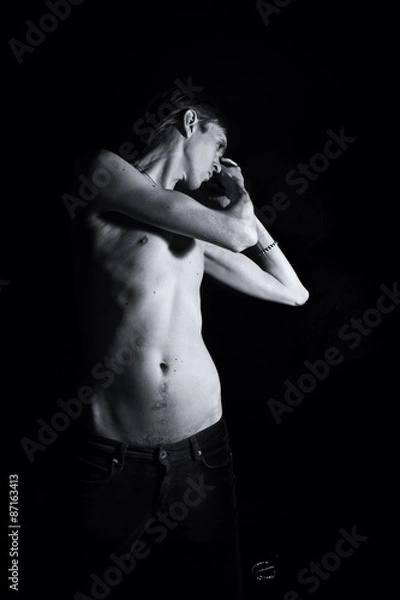 Fototapeta young slender naked man on a black background