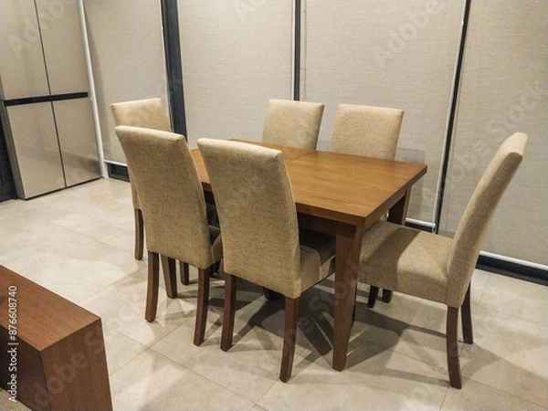 Fototapeta A dining table with six chairs arranged neatly in the family room.