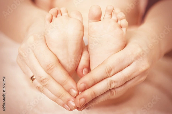 Fototapeta Newborn baby feet on female hands, close-up