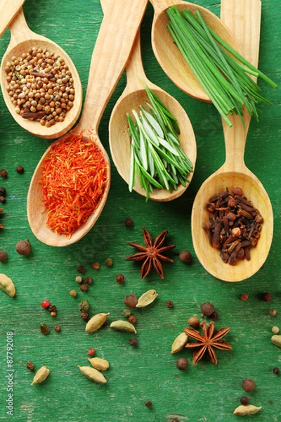 Fototapeta Wooden spoons with fresh herbs and spices on wooden background