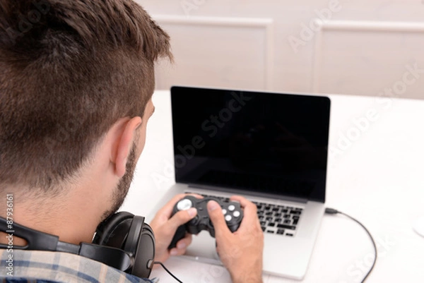 Fototapeta Young man playing computer games at home