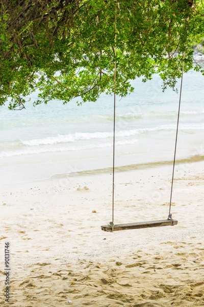 Fototapeta Swing in tree shade on a tropical beach