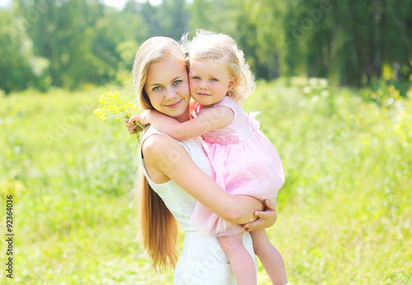 Fototapeta Mother holding on hands child hugging in summer day