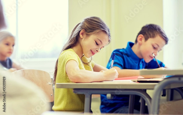 Fototapeta group of school kids writing test in classroom