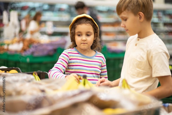 Fototapeta Kids little cute girl and teenager boy shopping for fresh organic fruits bananas and vegetables in supermarket