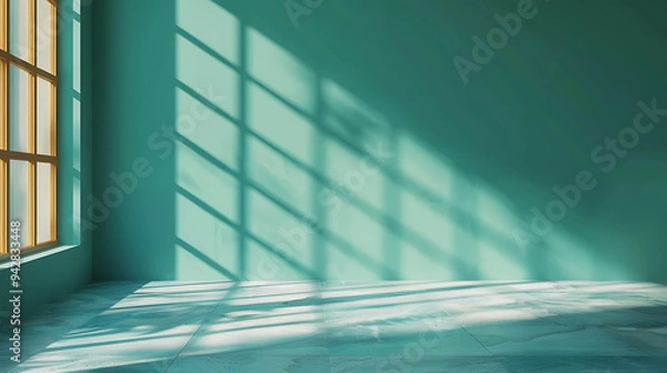 Fototapeta Sunlight streams through a window, casting geometric shadows on a teal wall and floor.