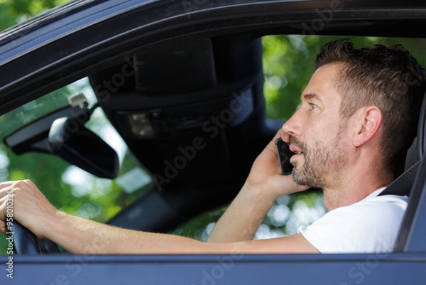 Obraz man talking on mobile phone while driving