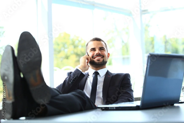 Fototapeta Portrait of businessman talking on mobile phone in office