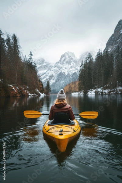 Fototapeta A person kayaking in lake water in winter with snow mountain