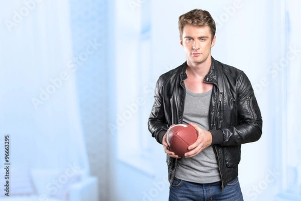 Fototapeta Young man football player portrait holding american football