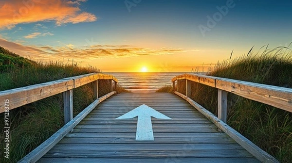 Fototapeta Wooden boardwalk leading to the sea with an arrow sign pointing towards it, directing towards the water, coastal path