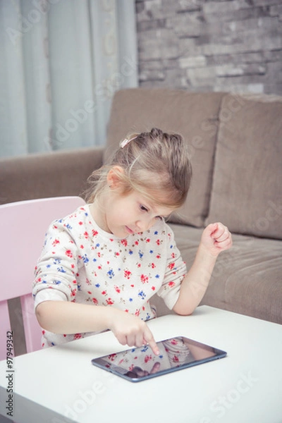 Fototapeta Cute little girl on table using digital tablet