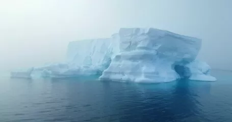 Obraz Gigantyczna góra lodowa dryfuje poranną mgłą oceaniczną na Antarktydzie. Tajemnicza dramatyczna scena mgły. Topnienie lodowców, wpływ zmian klimatycznych na środowisko polarne. Podróże i eksploracja Antarktyki. Strzał z drona z bliska